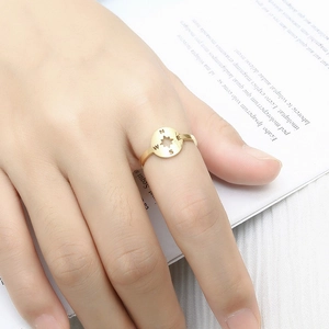 Detailed view of adjustable gold compass ring featuring engraved cardinal directions