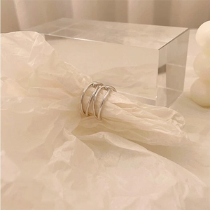 Detailed close-up of a silver multi-layer knot ring on a textured white surface
