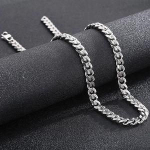 Macro view of polished silver titanium steel cuban link chain on a dark cylinder