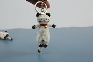 Handmade crochet cat keychain in white and brown with a small golden bell and metal ring