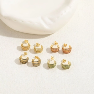Close-up of gold-plated C-shaped earrings with rows of white, purple, blue and green zircons