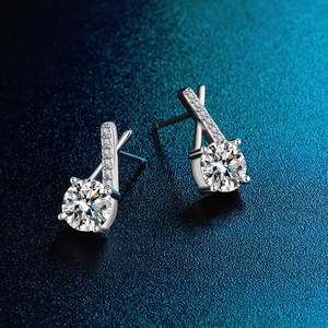 Close-up of D color moissanite earrings in 925 silver on deep blue textured backdrop