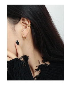 Detail of minimalist gold U-shaped earrings and ear cuffs on model with sleek styling