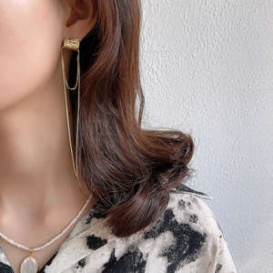 Detail of 925 silver golden long tassel earrings and pearl necklace on model