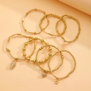Detailed close-up of gold-layered bracelet set featuring religious and heart-shaped charms