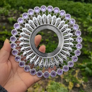 Detailed close-up of a silver metal wall decor piece featuring purple rhinestones and hollow patterns