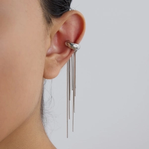 Detail view of silver stainless steel ear cuff with long tassel chains on a model ear