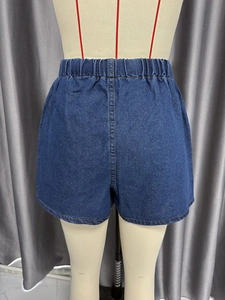Detail of blue denim shorts showing elastic high waist with orange contrast stitching