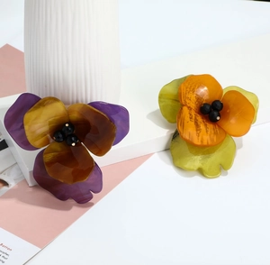 Close-up of handmade acrylic flower brooches with marble textures and black bead centers