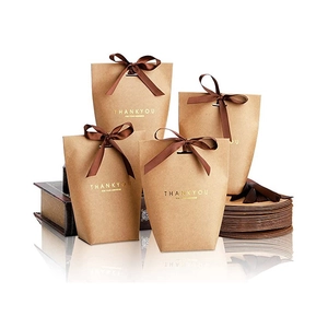Detailed macro view of trapezoid kraft paper gift bags with gold foil text and brown ribbon