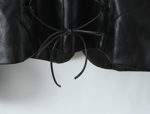 Détail du laçage réglable sur la taille d'une veste noire en similicuir
