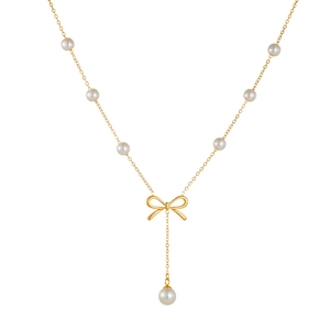 Ensemble collier doré avec pendentif papillon, perles blanches et pompon sur fond blanc épuré