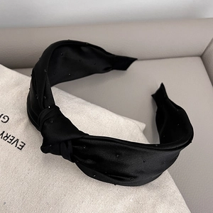 Close-up of black knot headband with shimmering beads on premium satin fabric