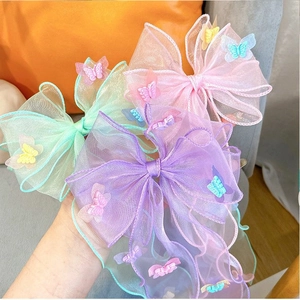 Detailed close-up of three organza bow hair clips in pink, purple and mint green colors