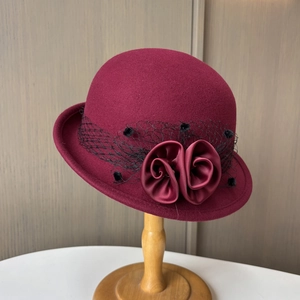 Close-up of burgundy wool felt hat featuring mesh veil and satin rose flower details
