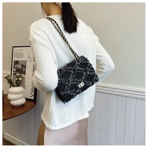Close-up of black denim crossbody bag featuring metal turn-lock and chain strap