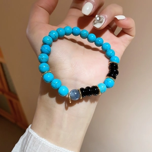 Close-up of turquoise beads with golden gear spacers and dark accents on a beaded bracelet