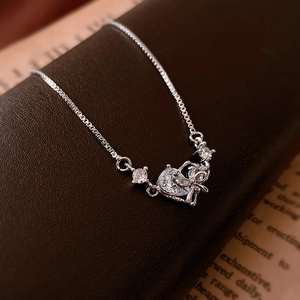 Silver heart and bow zircon bracelet with adjustable box chain on vintage book background