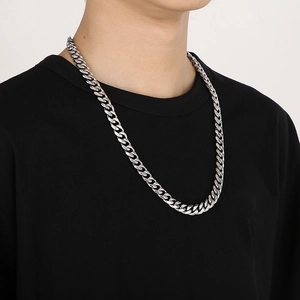 Close-up of men's chunky silver Cuban link chain in polished steel on a model's neck