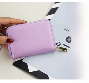 Detail of purple litchi grain leather card holder with secure golden metal zipper closure