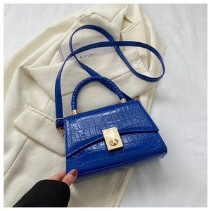 Detail of blue faux crocodile texture and gold twist lock on stylish handbag