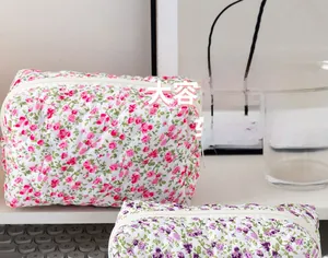 Detail of pink and purple floral quilted makeup bags on a desk with zipper closure