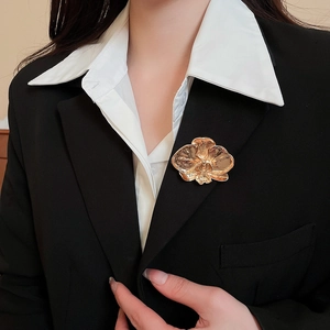 Macro detail of a golden orchid flower brooch pinned on a black blazer lapel