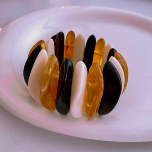 Macro detail of acrylic geometric bracelet showing black, cream, and amber resin textures