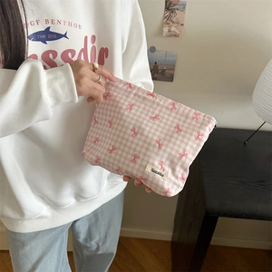 Close-up of pink floral cosmetic bag with bow pattern and brand label detail