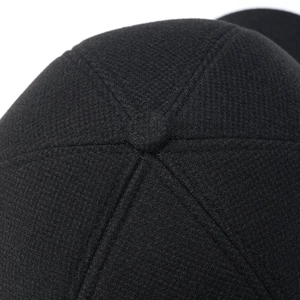 Macro shot of stitching details and top button on a black winter baseball cap