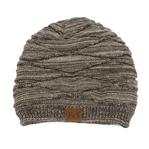 Close-up of mixed brown knit texture and faux leather logo label on a winter beanie