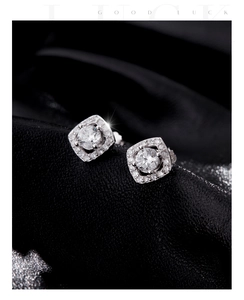 Macro shot of silver square halo stud earrings with sparkling round center stone on black leather