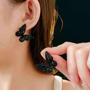 Detail of black butterfly stud earrings with shimmering stones on a dark background