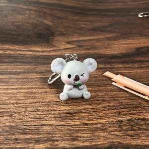 Close-up of cute grey resin koala keychain on a dark wood background with metal ring