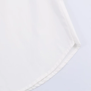 Detailed close-up of a white poplin shirt featuring curved hemline and fine woven texture