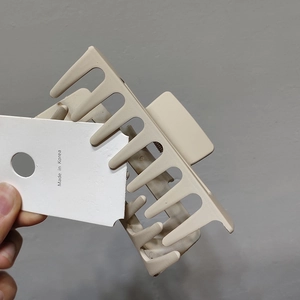 Detail of a large matte beige shark hair claw clip with a Made in Korea tag