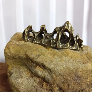 Macro detail of bronze mountain paperweight with textured finish on natural rock base