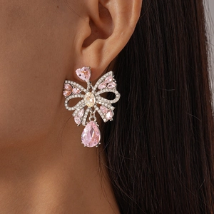 Détail de boucles d'oreilles nœud argenté avec cristal rose en goutte et pierres brillantes