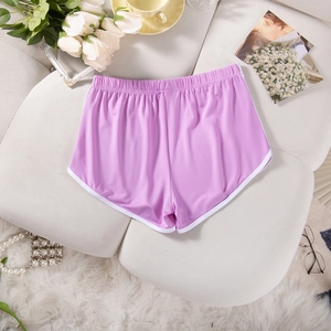 Flat lay of lavender women's yoga shorts with white trim on a plush sofa