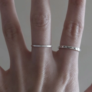 Detail of 925 sterling silver star pattern ring and textured band on finger