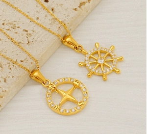 Detailed view of gold rudder and compass pendants featuring sparkling cubic zirconia