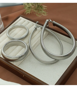 Macro detail of textured silver steel jewelry set including two bangles and a necklace