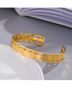 Macro detail of 14K gold plated C-shaped cuff bracelet with hammered metal discs