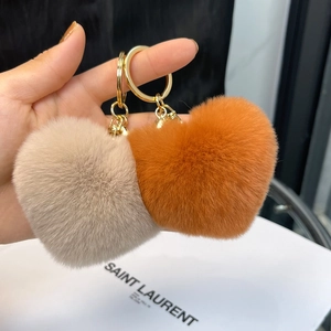 Detail view of plush heart keychains in beige and orange with golden metal rings