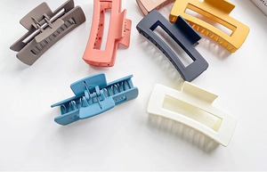 Flat lay of square matte claw clips in gray, peach, yellow, navy, teal, and beige