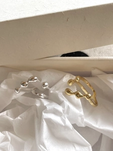 Close-up of gold and silver irregular liquid-style rings in a beige jewelry gift box