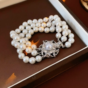 Macro shot of three-row pearl bracelet with floral diamond clasp in a premium jewelry box