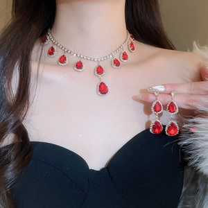 Detailed view of model wearing a luxury gold-plated jewelry set with red teardrop gems
