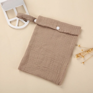 Detail of brown cotton gauze stroller bag with resin snap buttons and natural soft texture