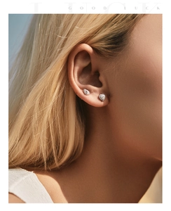 Close-up of heart and pear-shaped moissanite stud earrings on ear for a chic silver look